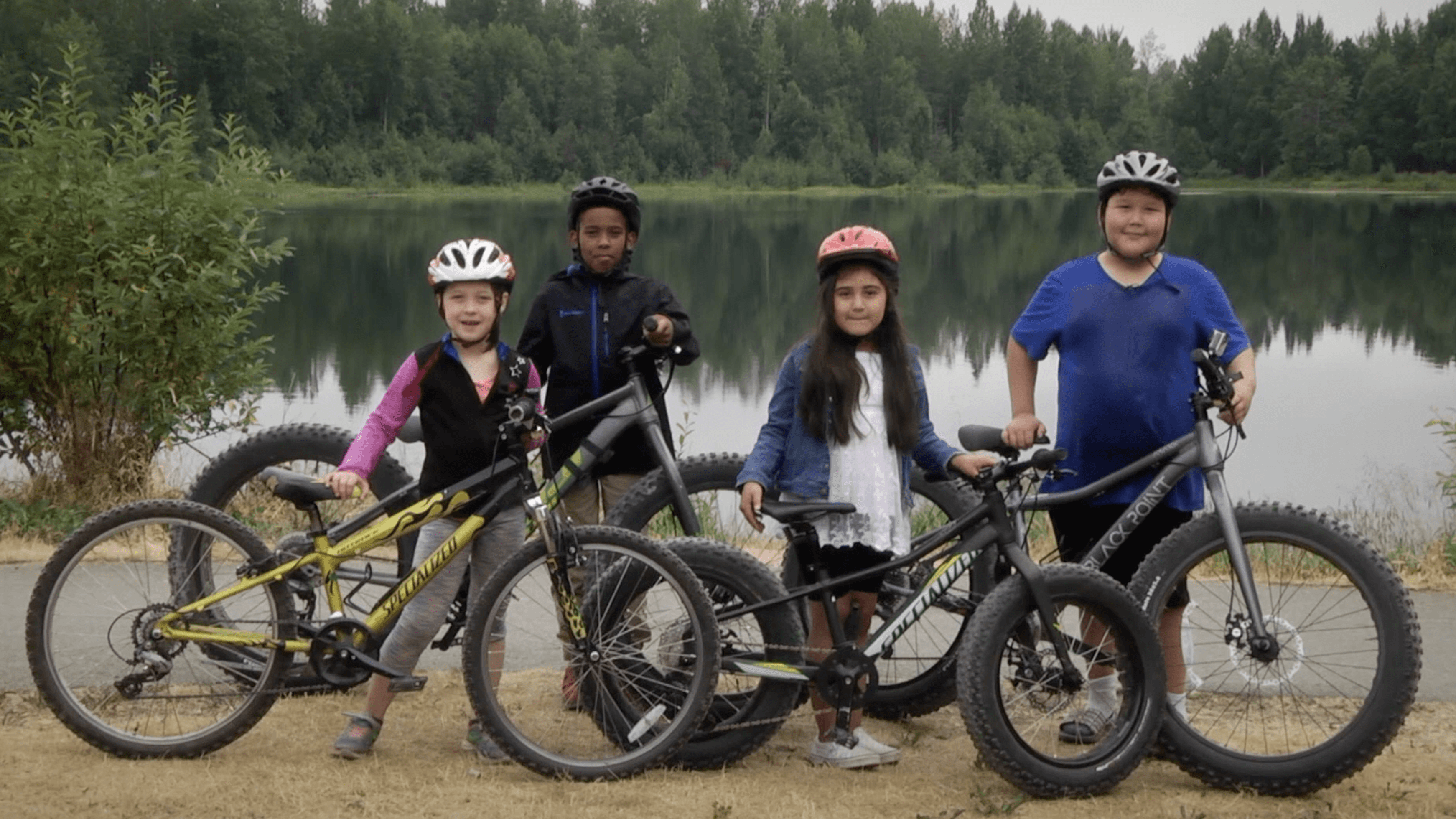 Kids check a safety diagram before biking along the Campbell Creek Trail in Anchorage.