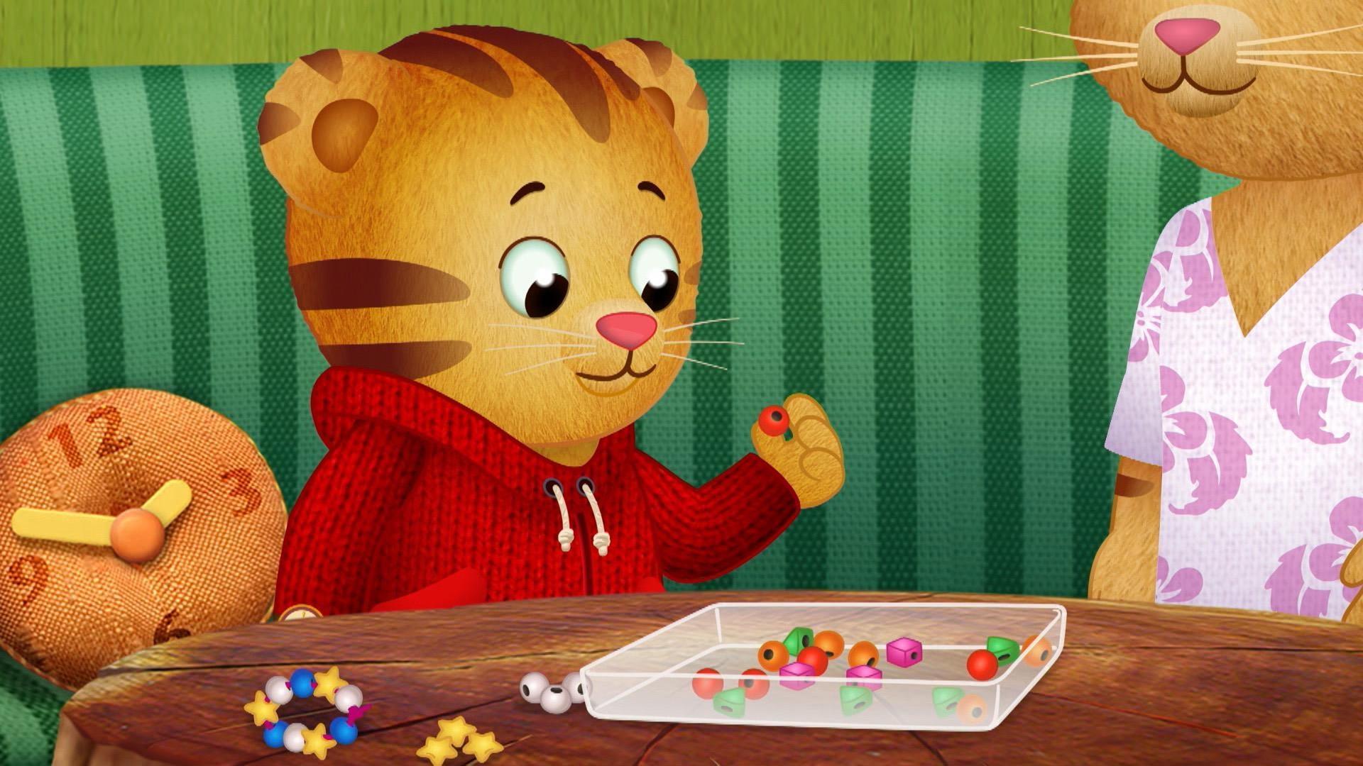 Daniel stops to appreciate the red beads he has and uses them to make a space bracelet.