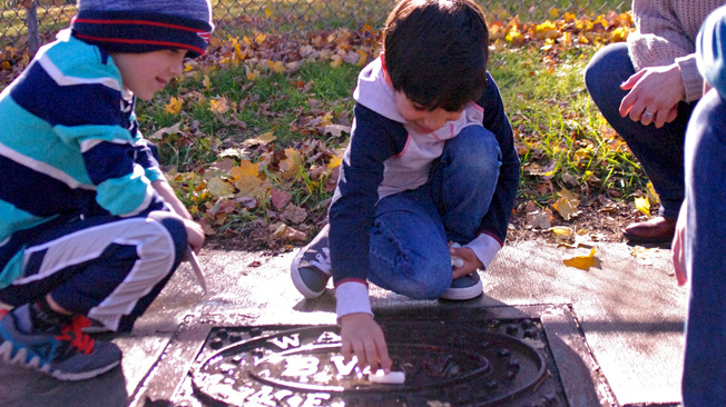 Boy floats object in puddle